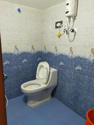 a bathroom with a toilet and a blue wall at Nest Home stay 