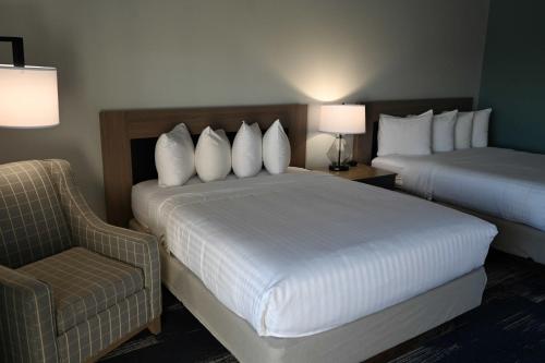 a hotel room with two beds and a chair at Edgewater Inn and Suites, an Ascend Collection Hotel in Coos Bay