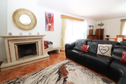 a living room with a black couch and a fireplace at Casa Panorâmica Gerês by Gerês Casas in Geres