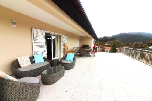 a patio with couches and chairs on a balcony at Casa Panorâmica Gerês by Gerês Casas in Geres