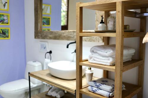 uma casa de banho com uma prateleira de madeira com toalhas e um lavatório em Solea Villa Tropical em Santa Marta