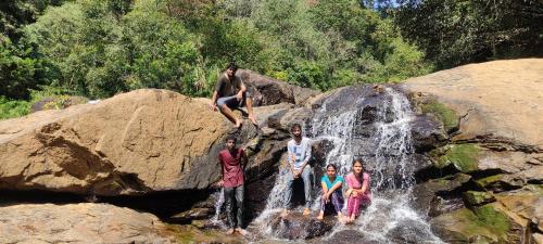 a group of people standing in front of a waterfall at Munnar Village Homes in Munnar
