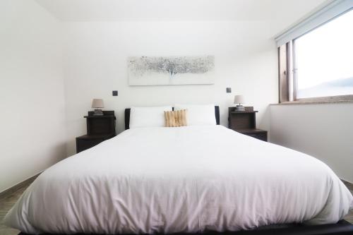 a white bed in a white bedroom with a window at Casa Panorâmica Gerês by Gerês Casas in Geres