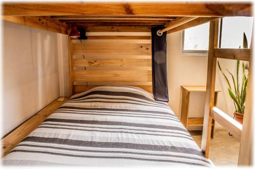 a bed in a room with a wooden wall at ATMA Hostel & Yoga in Huanchaco