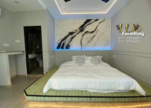 a bedroom with a white bed with a painting on the wall at I Do Farmstay in Bukit Mertajam