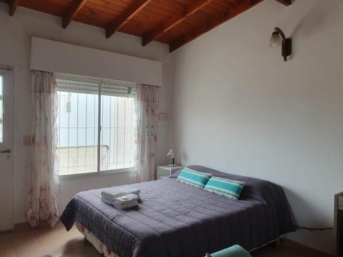 een slaapkamer met een bed met blauwe lakens en een raam bij APA Jazmín Sur 1 y 2 - tranquilo complejo residencial in Puerto Madryn