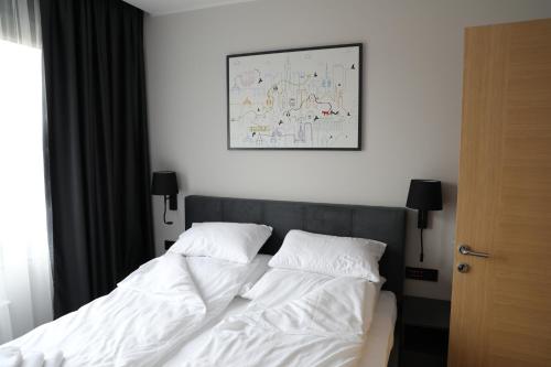 a bed with white sheets and pillows in a bedroom at Moaline Apartments, free parking in Sarajevo