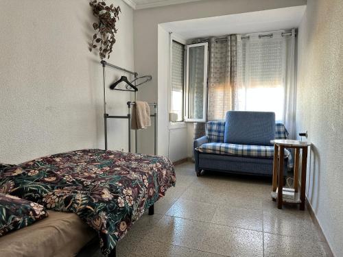 a bedroom with a bed and a chair and a window at Casa Angela de Novelda in Novelda