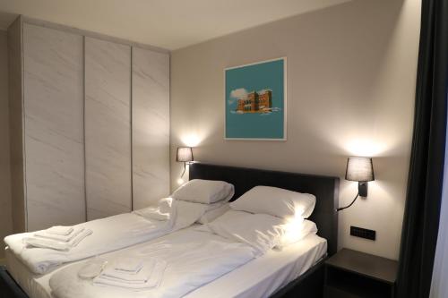 a bedroom with a bed with white sheets and pillows at Moaline Apartments, free parking in Sarajevo