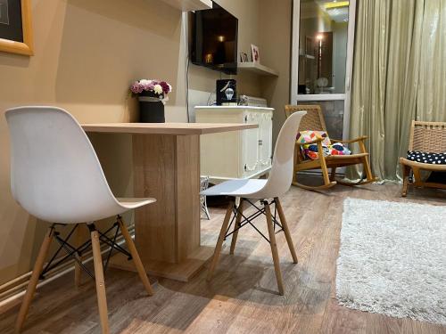 una cucina con due sedie bianche e un tavolo di Downtown Zemun Studio Apartment a Belgrado