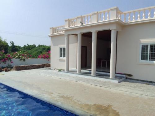 a villa with a swimming pool and a house at Rivera Resort- Night stay in Jammalamadugu