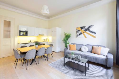 Exclusive & Spacious Central Residence w/ 4BEDRM 2BATHRM في بودابست: غرفة معيشة مع أريكة وطاولة ومطبخ