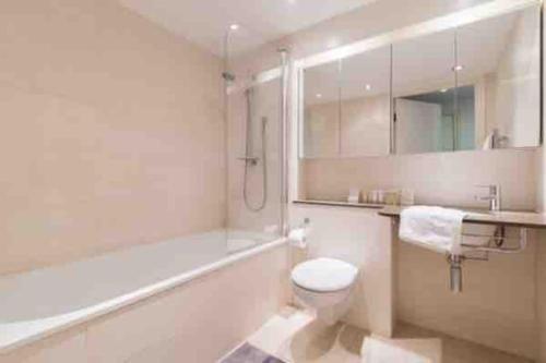 a bathroom with a tub and a toilet and a sink at Hyde Park Apartment in London