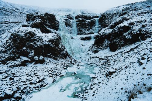 a waterfall on a mountain with snow on it at Hotel Studlagil in Skjöldólfsstaðir