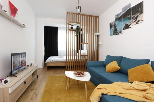 uma sala de estar com um sofá azul e um quarto em Apartament Modern Ivory Pipera em Voluntari