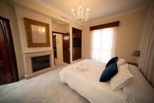 1 dormitorio con 1 cama con chimenea y lámpara de araña en Villa candelaria luxury home, en Bormujos