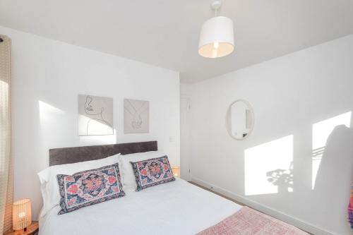 a white bedroom with a bed with two pillows at Bluebell Cottage Mumbles - Sea Views in The Mumbles