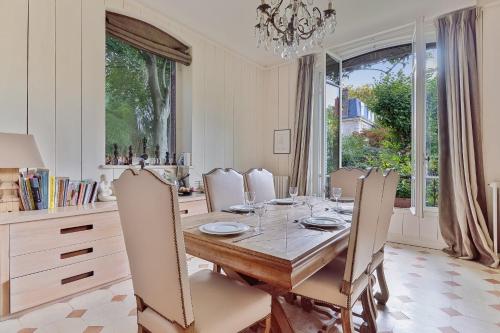a dining room with a table with chairs and a chandelier at Villa Boileau - Welkeys in Paris