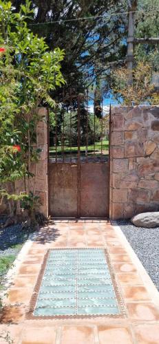 una puerta de hierro con una pared de piedra y un camino de piedra en Domenica Casa Hotel en La Cumbre