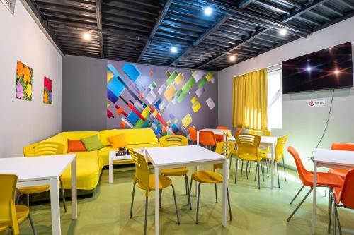 a room with a yellow couch and tables and chairs at Green Cube Capsule Hostel in Sofia