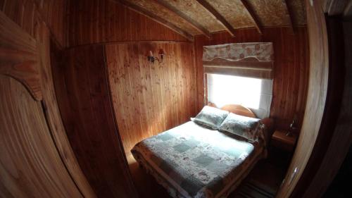 a small room with a bed and a window at Los arrayanes de huife pucon in Termas De Huife