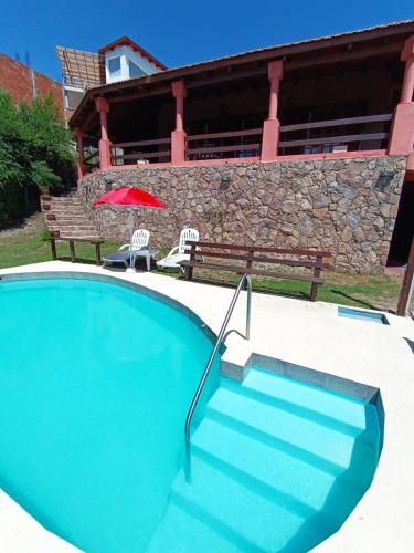 einen Pool mit einem roten Regenschirm und einer Bank in der Unterkunft Chalet Fer Icho in Villa Icho Cruz