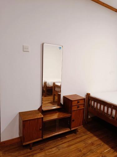 a mirror on a dresser next to a bed at Magnolia Hideout in Nuwara Eliya