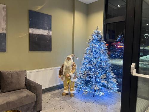 a person standing next to a blue christmas tree at Delux apartment next to ice rink in Gudauri