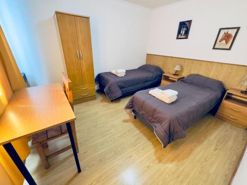 a room with two beds and a table and a desk at Apartment Al Sur in Malargüe