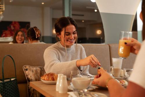 a woman sitting at a table eating food at The Address Glasgow in Glasgow