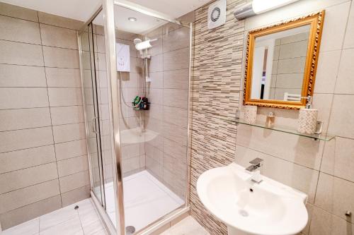 a bathroom with a shower and a sink and a mirror at Large studio 2min to hendon Central Station in The Hyde