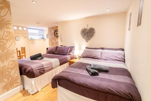 two beds in a room with a heart on the wall at Large studio 2min to hendon Central Station in The Hyde