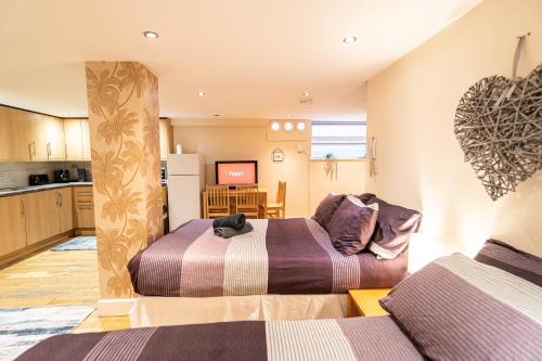two beds in a room with a kitchen at Large studio 2min to hendon Central Station in The Hyde