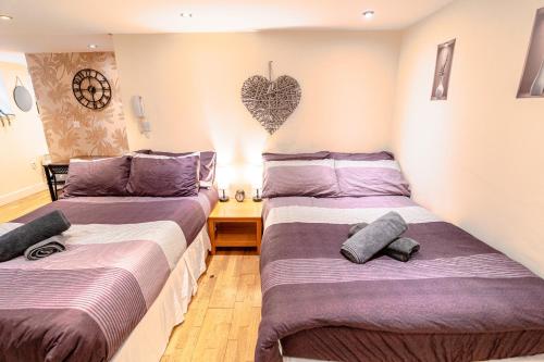 two beds in a room with a heart on the wall at Large studio 2min to hendon Central Station in The Hyde