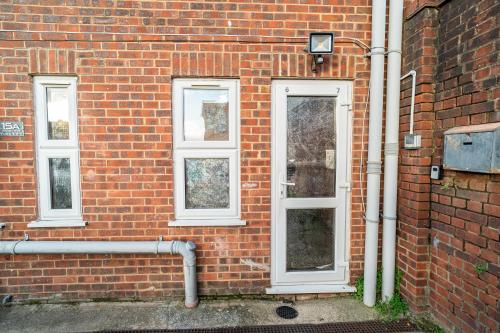 a brick wall with a door and three windows at Large studio 2min to hendon Central Station in The Hyde