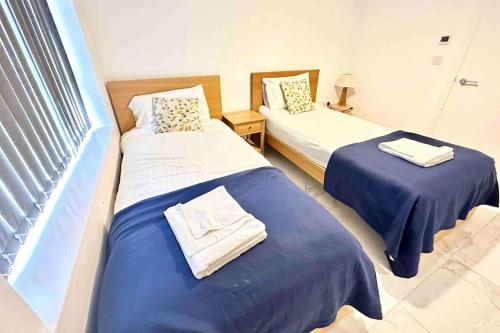 two beds in a room with blue sheets at Paradigm House, Luxury 2-Bedroom Apartment 3, Free Parking, Oxford in Oxford