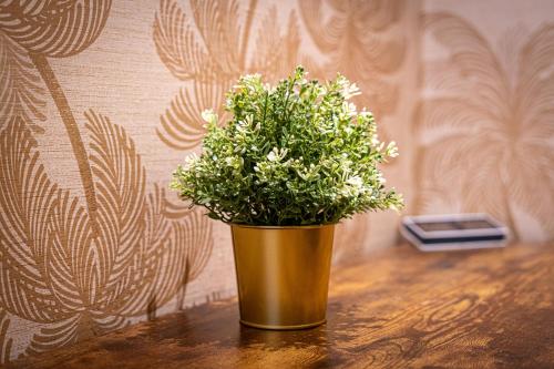 a gold vase with a plant on a table at Large studio 2min to hendon Central Station in The Hyde