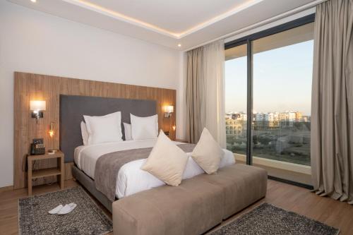 a bedroom with a large bed and a large window at Dominium Hotel in Agadir