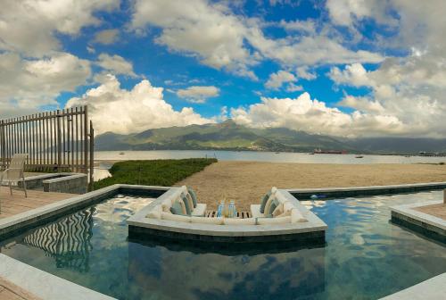 a swimming pool with a boat in the water at Ágape Suítes & Apartamentos in São Sebastião