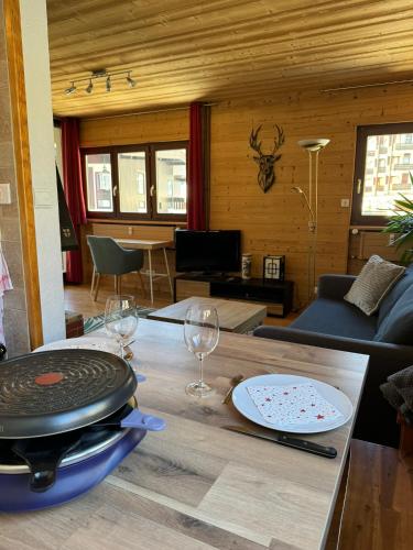 - un salon avec une table et des verres à vin dans l'établissement Appartement T2 ambiance chalet centre village proche des commerces et des pistes WIFI, à La Clusaz
