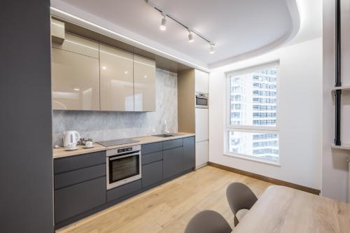 una cocina con armarios grises y una mesa con sillas. en Aperto Apartament Gdynia centrum 10 piętro, en Gdynia