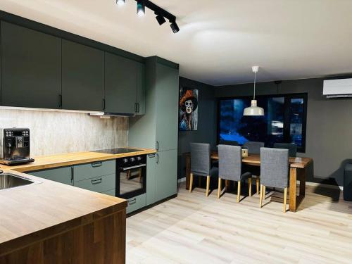 una cocina con armarios verdes, mesa y sillas en Familievennlig Apartment en Tvedestrand