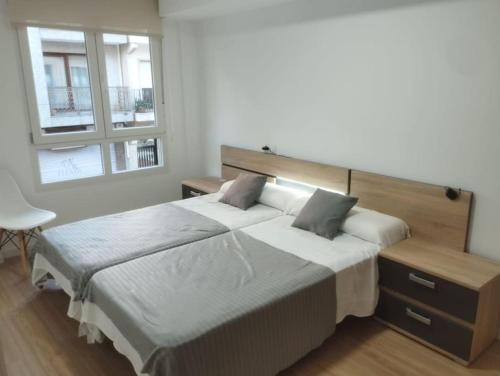 Dos camas en un dormitorio con dos ventanas. en Apartamento Bulevar Cangas, en Cangas de Morrazo