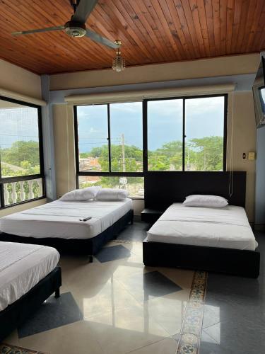 a bedroom with two beds and large windows at Casa Raices in La Dorada