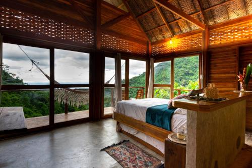 ein Schlafzimmer mit einem Bett in einem Zimmer mit Fenstern in der Unterkunft Paraiso Ahimsa in Buritaca