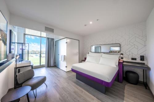 Founex的住宿－YOTEL Geneva Lake，酒店客房带一张床铺、一张书桌和一间卧室