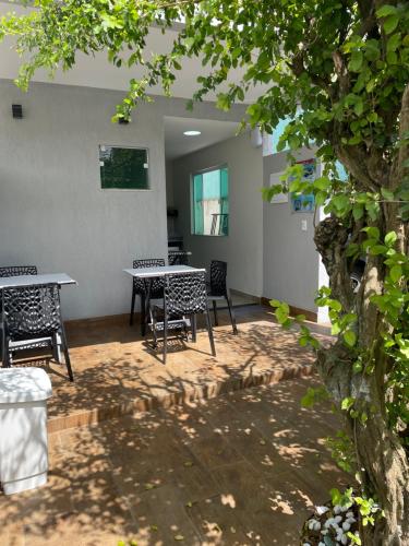 a patio with chairs and a table and a tree at Brisa dos Anjos Suítes in Arraial do Cabo