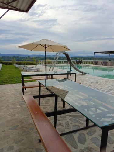 two picnic tables with an umbrella and a slide at Finca Maratón Alto in Calarcá