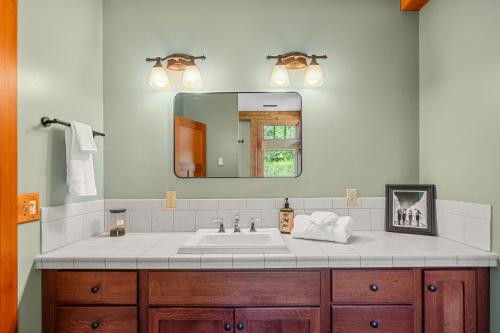 La salle de bains est pourvue d'un lavabo et d'un miroir. dans l'établissement Walk to Village! Stunning timber chalet! Hot-Tub, Bonfire & more!, à Ellicottville