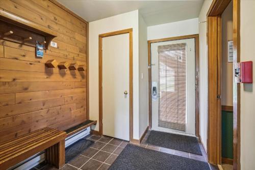 a hallway with a wooden wall and a door at Trail Creek 11 in Killington